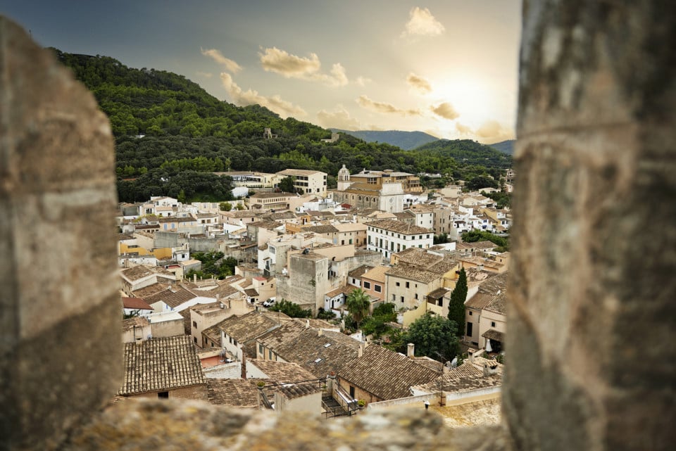 Scenic Spanish village nestled around mountains under a golden sunset sky
