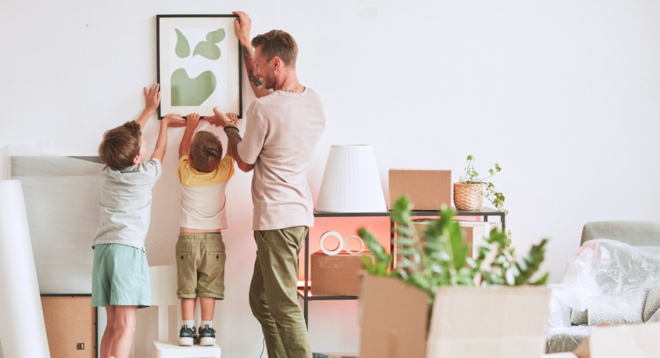 Beautiful newly moved-in family hanging a picture together in a house sold by lucas fox