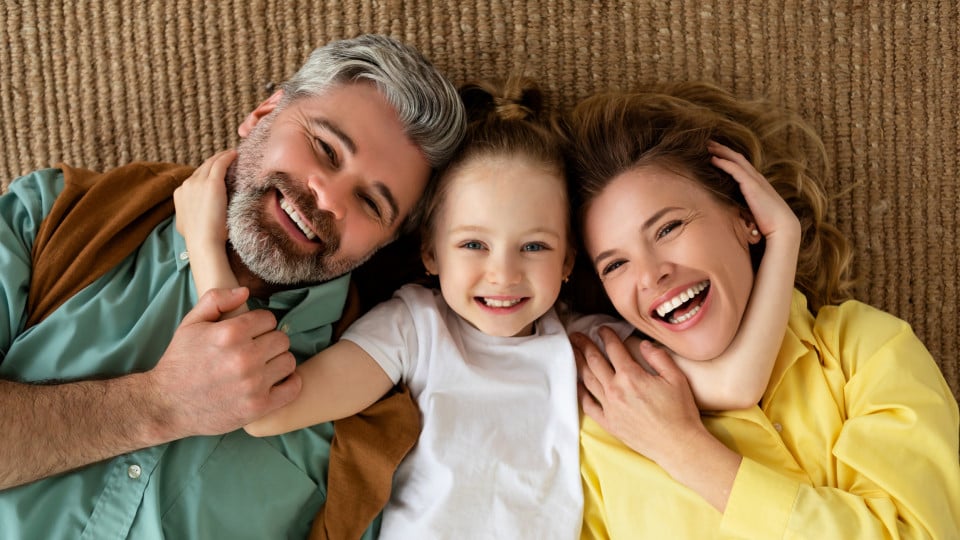 Father and mother with daughter lying on a rug in their new home purchased at Lucas Fox