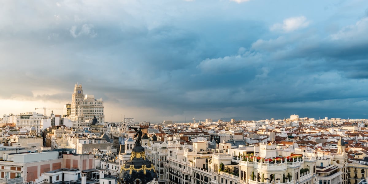 Panoramic view of Madrid city center featuring the iconic Metropolis Building and Gran Vía at sunset.