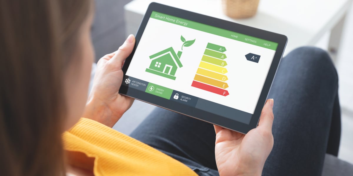Person checking a home's energy efficiency on a tablet using a real-time monitoring app.
