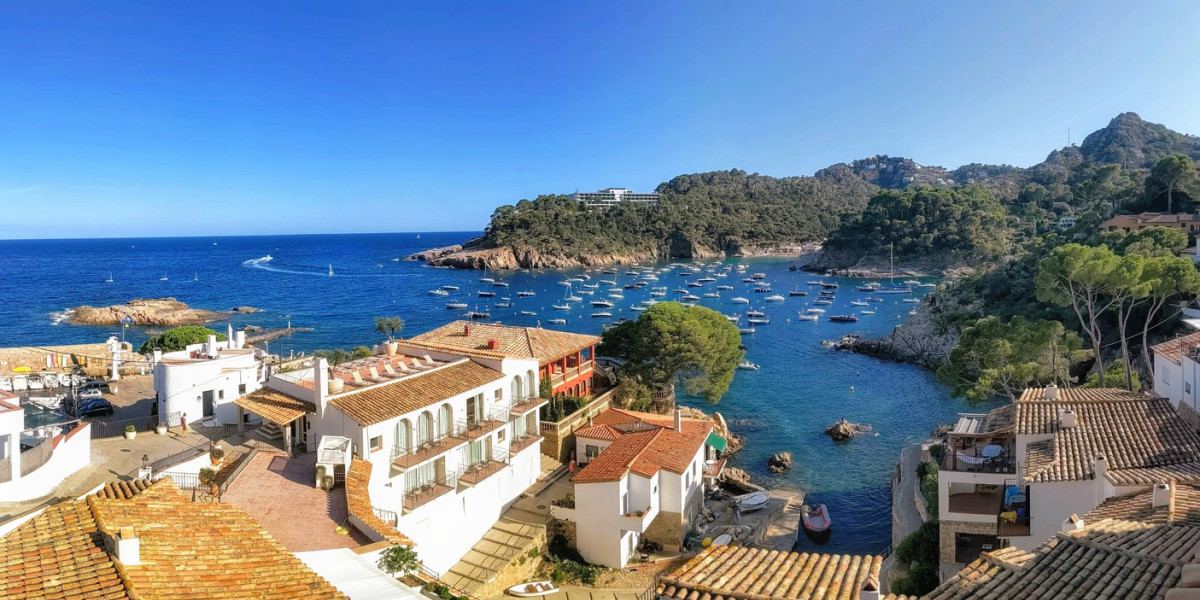 Scenic view of a bay in Mallorca with coastal houses and boats anchored in the turquoise sea.