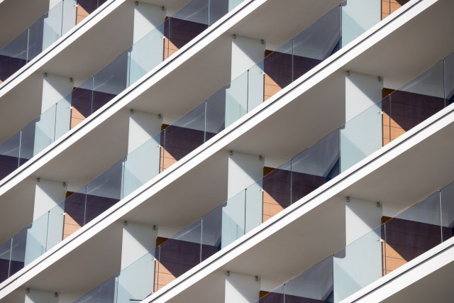 Modern luxury building with transparent glass balconies and panoramic views, upscale residential property with contemporary architectural design