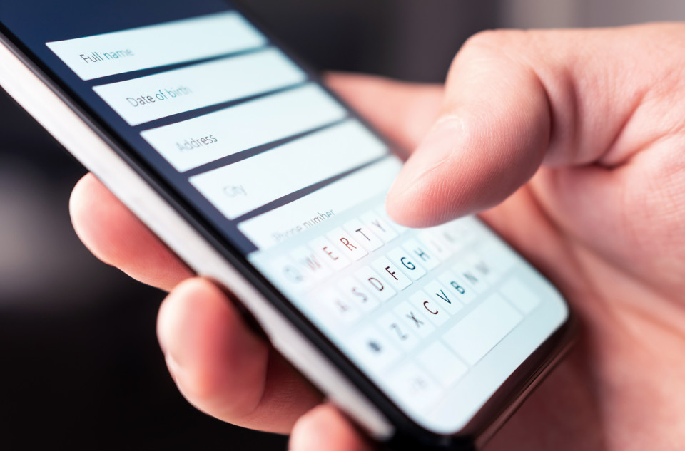 A person registering a property on a mobile phone, holding the device in their hands.