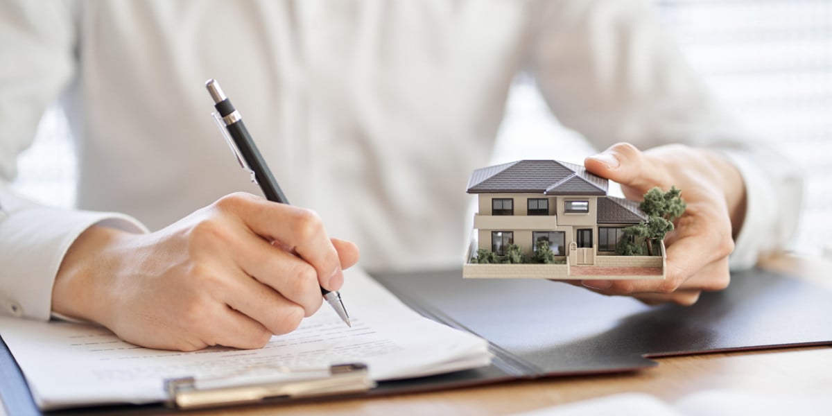 A person registering a property, thoughtfully considering a house, with a form and a house icon visible on the screen.