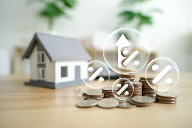 Illustration of a house next to stacks of money with a elements showing tax information, symbolizing property taxes.