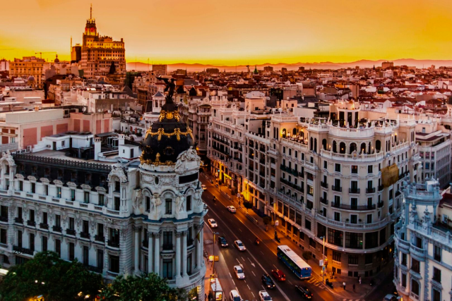 Panoramic view of Madrid’s Gran Vía at sunset, featuring the Metropolis Building and the city’s elegant historic architecture.