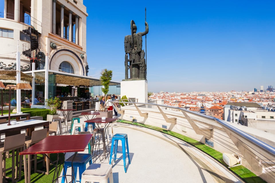 Rooftop terrace in Madrid with panoramic views of the city center and an iconic statue, a cosmopolitan leisure spot.
