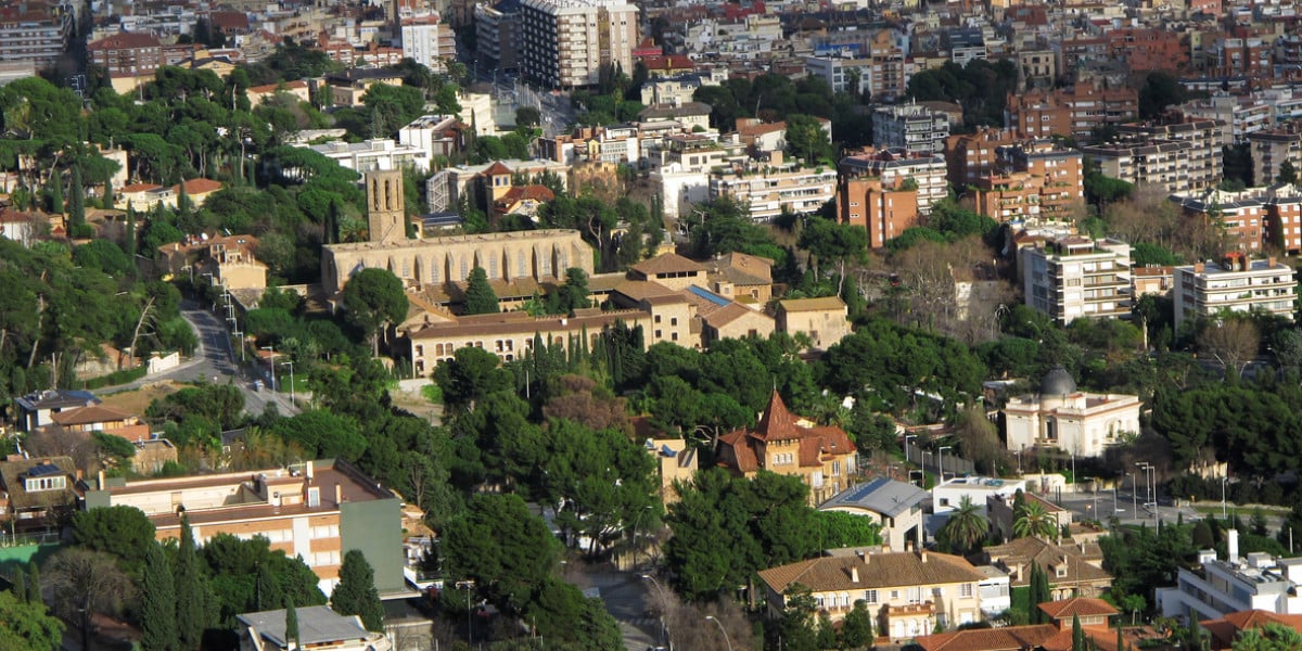 Aerial view of the Zona Alta of Barcelona showing elegant residential buildings surrounded by greenery and historic landmarks.