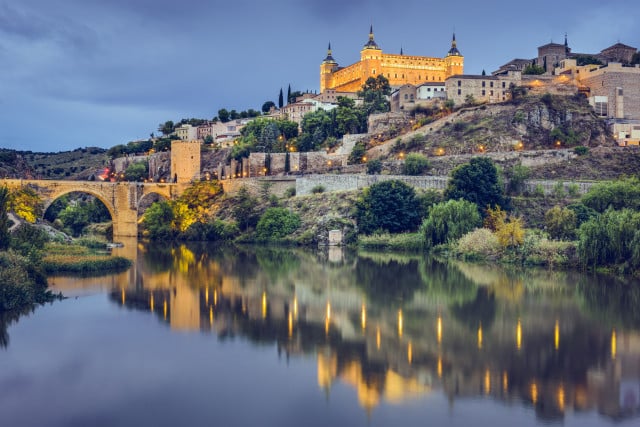 Beautiful view of Toledo where we see the river and in the background the castle illuminated by the lights of the city at sunset.